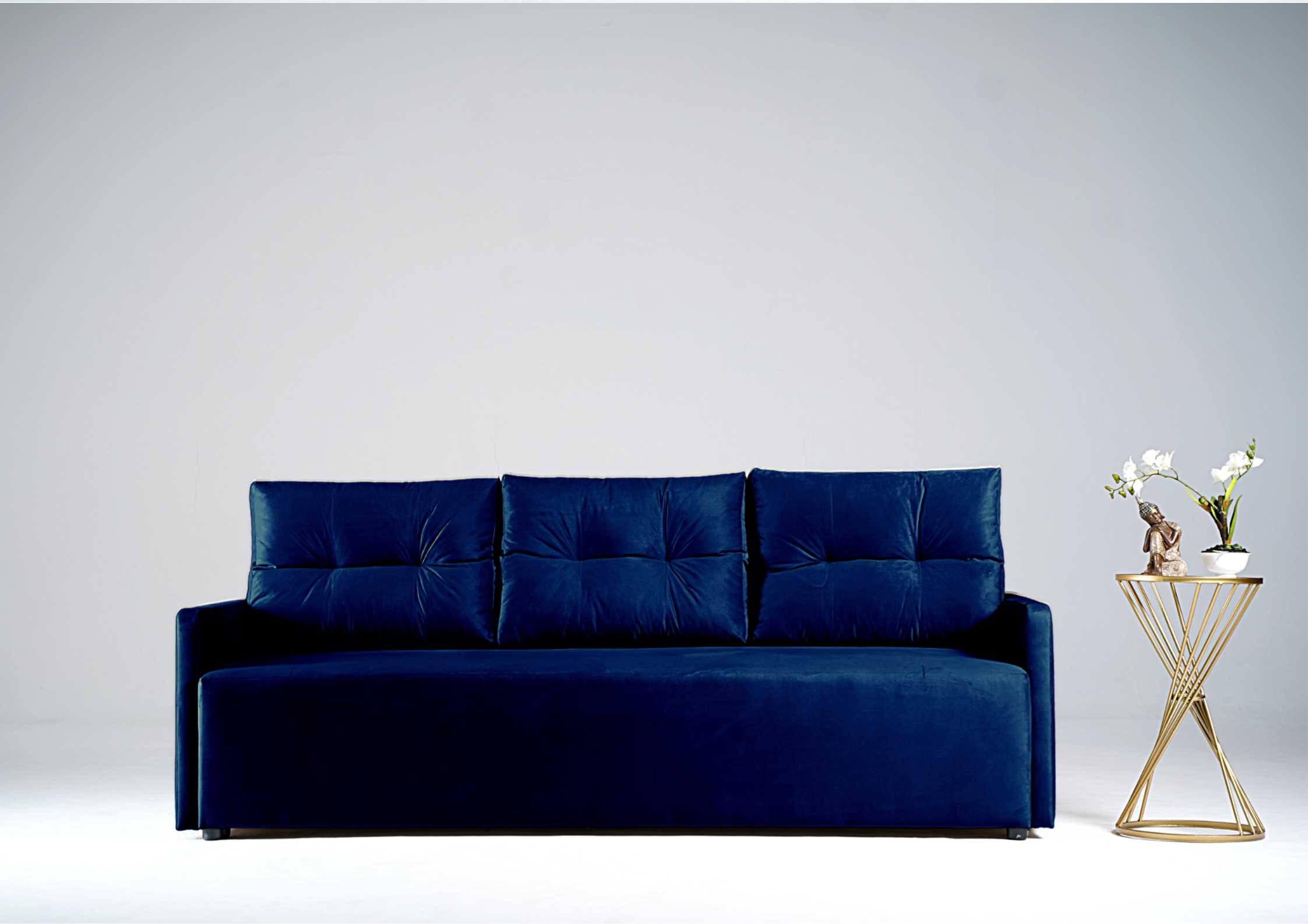 Granatowa sofa z pikowanymi poduszkami